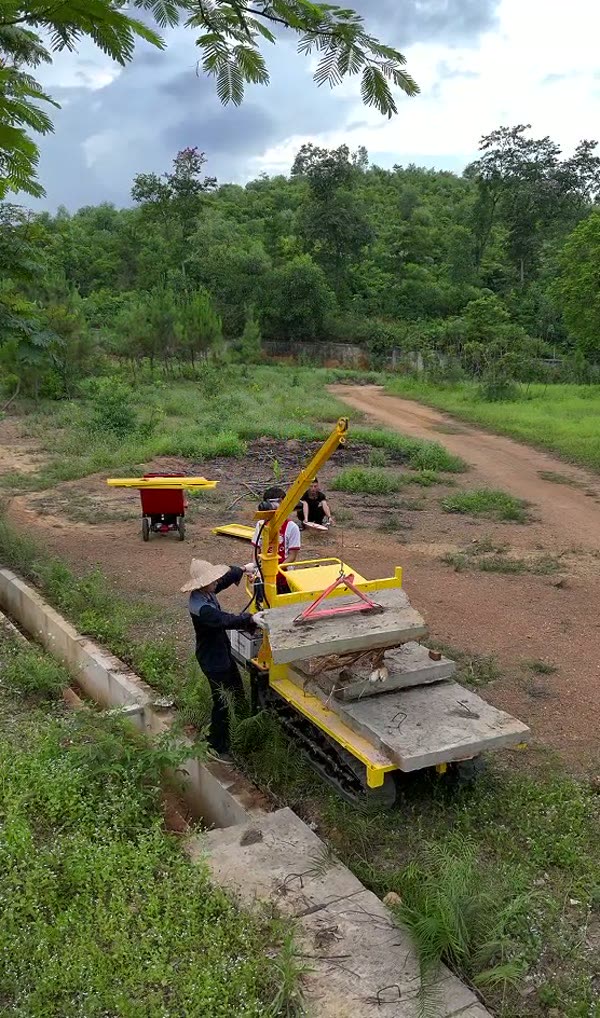 Xếp tấm bê tông đúc sẵn lên thùng xe rùa bánh xích cạnh bờ mương