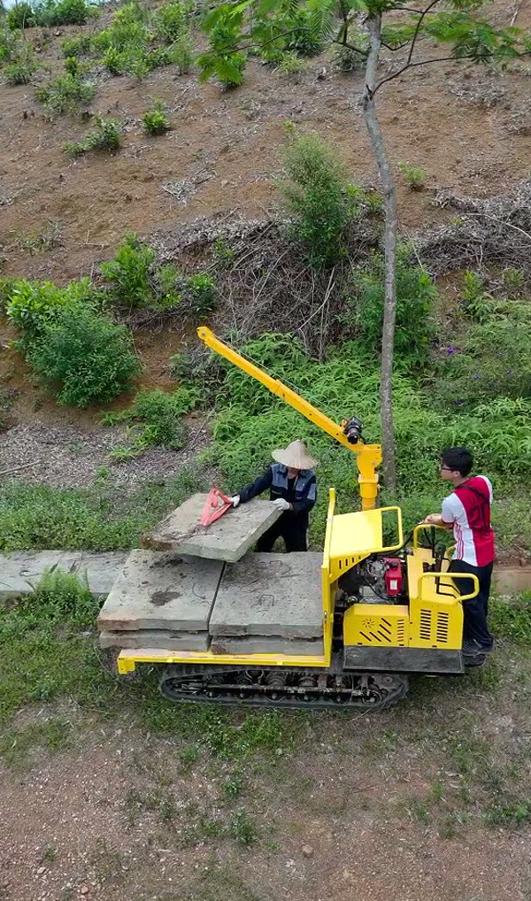Xe rùa bánh xích có cẩu chở chồng tấm bê tông dưới chân đồi